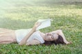 Asian woman lying on grass field for reading in the park Royalty Free Stock Photo