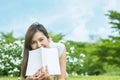 Asian woman lying on grass field with white book in the park Royalty Free Stock Photo
