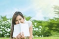 Asian woman lying on grass field with white book in the park Royalty Free Stock Photo