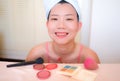 Asian woman and makeup - young happy and beautiful Chinese girl with towel head wrap smiling cheerful at bathroom mirror preparing Royalty Free Stock Photo