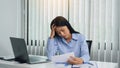 Asian woman manager is stressed and has a headache about faulty work documents at her office Royalty Free Stock Photo