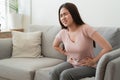 Asian woman with menstruation and pain period cramps. young women having painful while sitting on sofa at her home