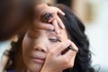 Asian woman model false eyelashes during make-up session. The make-up artist is applying a black eyeliner with the brush on eyelid Royalty Free Stock Photo