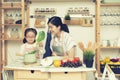 Asian woman mom and daughter play together in kitchen,mom hold tablet for teach little girl how to cook,process in vintage style