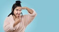 Asian woman with mustache playfully imitates Chinese kung fu fighter against blue background. House wife With sense of