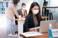 Asian woman office worker wearing face mask working in new normal office and doing social distancing during corona virus