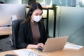 Asian woman office worker wearing face mask working in new normal office and doing social distancing