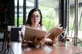 Asian woman open menu for ordering in coffee cafe and restaurant and smiling for happy time Royalty Free Stock Photo