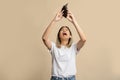 Asian woman is opening empty wallet. Upset crying female model standing isolated over light brown studio background wall Royalty Free Stock Photo