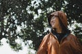 Asian woman in an orange raincoat is outdoors. She was smiling and happy