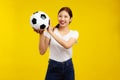 Asian woman over isolated yellow background holding a soccer ball, smiling and looking at camera, sport concept Royalty Free Stock Photo
