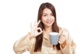 Asian woman in pajamas show OK with toothbrush in mug Royalty Free Stock Photo