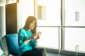 Asian woman passenger holding mobile phone and checking flight or online check in and travel planner at international airport