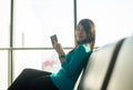 Asian woman passenger holding passport and checking flight or online check in and travel planner at international airport