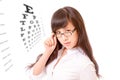 Asian woman peering over top of spectacles next to eyechart Royalty Free Stock Photo