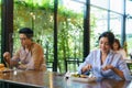 Asian woman and asian people eating food alone at table with plexi screen between table in reopening restaurant after lockdown