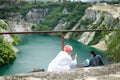 Asian Woman Photographer hold mobile phone camera point to shoot lying woman over cliff Royalty Free Stock Photo