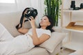 Asian woman photographer lying at home on couch and looking at photos in camera, freelance photographer work for self Royalty Free Stock Photo