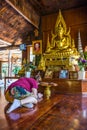 Asian woman pilgrim prostrating oneself in front of the Buddha statues in hall of Wat Tham Khao Wong