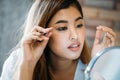 Asian woman placing decorative eyelashes on eye