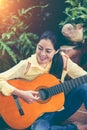 Asian woman playing acoustic guitar with bright sunlight. Vinta Royalty Free Stock Photo