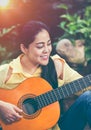 Asian woman playing acoustic guitar with bright sunlight. Vinta Royalty Free Stock Photo