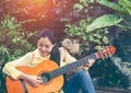 Asian woman playing acoustic guitar with bright sunlight. Vinta Royalty Free Stock Photo