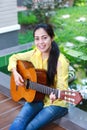 Asian woman playing classic guitar, outdoor at daytime with brig Royalty Free Stock Photo