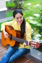 Asian woman playing classic guitar, outdoor at daytime with brig Royalty Free Stock Photo