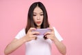 Asian woman playing games on mobile phones on a pink background Royalty Free Stock Photo