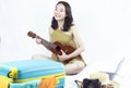 Asian woman playing guitar while preparing clothes for summer trip