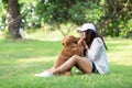 Asian woman playing and hug young dog golden retriever friendship dog in outdoor the nature park background. Royalty Free Stock Photo