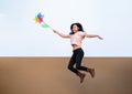 Asian woman posts, play and JUMPS with Windmill Toy colourful rainbow colour on the building rooftop in sunset time Royalty Free Stock Photo