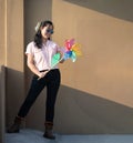 Asian woman posts and play Windmill Toy colourful rainbow colour on the building rooftop in sunset time Royalty Free Stock Photo