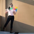 Asian woman posts and play Windmill Toy colourful rainbow colour on the building rooftop in sunset time Royalty Free Stock Photo