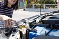 Asian woman pouring clean water from bottle into the windshield washer fluid tank of a car,female filling the windshield washer Royalty Free Stock Photo