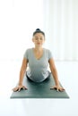 Asian woman practicing yoga , stretching in Cobra exercise, Bhujangasana pose, working out, indoor Royalty Free Stock Photo