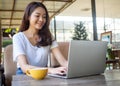 Asian woman pretty face wearing a white shirt, sitting and working in a coffee shop Royalty Free Stock Photo