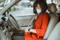 Woman in protective mask driving a car on road. Safe traveling fasten seat belt Royalty Free Stock Photo