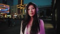 Asian woman puts on headphone at night city
