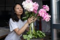 Asian woman puts peonies flowers in vase. Sweet home. Allergy free. Royalty Free Stock Photo