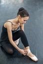 Asian woman puts on pointe shoes by tying ribbons on her ankle. Royalty Free Stock Photo