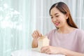 Asian woman putting money coin in to house piggy bank metaphor saving money financial for buy the home Royalty Free Stock Photo