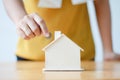 Asian woman putting money coin in to house piggy bank metaphor s