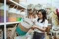 Asian woman raises wicker baskets standing among the handicraft items