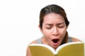 Asian woman reading book and gape feel sleepy on white background, Selective focus, Face expression concept