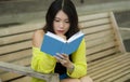 Asian woman reading book - lifestyle portrait of young beautiful and happy Korean girl reading novel or studying relaxed outdoors Royalty Free Stock Photo