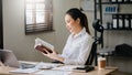 Asian woman reading book while sitting at in cafe or home office Royalty Free Stock Photo