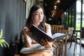 Asian women reading and smiling and happy Relaxing in a coffee shop after working in a successful office Royalty Free Stock Photo