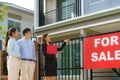 Asian woman Real estate broker agent showing a house detail in her file to the young Asian couple lover looking and interest to Royalty Free Stock Photo